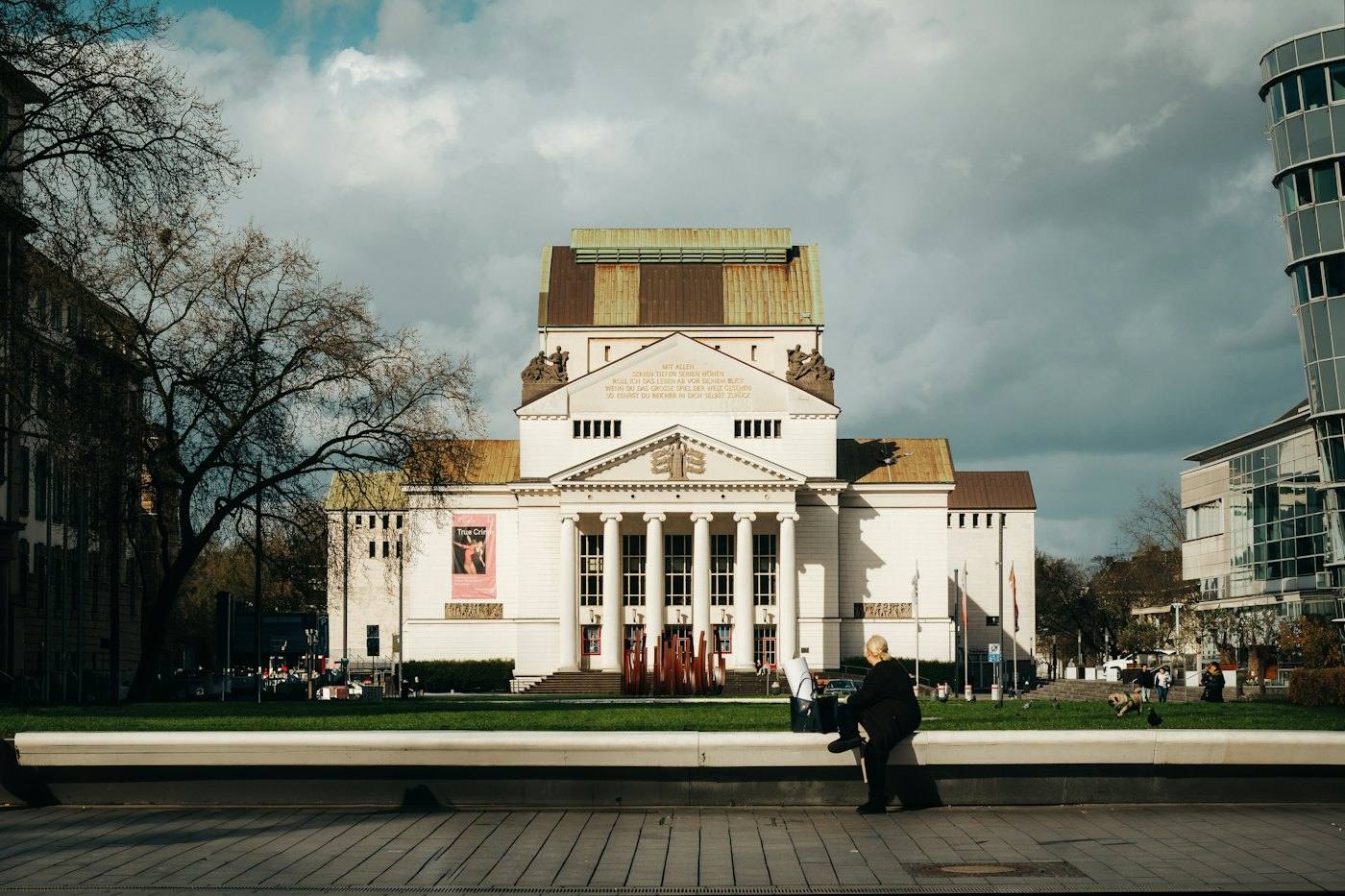 White theatre building with a columned portal behind a square