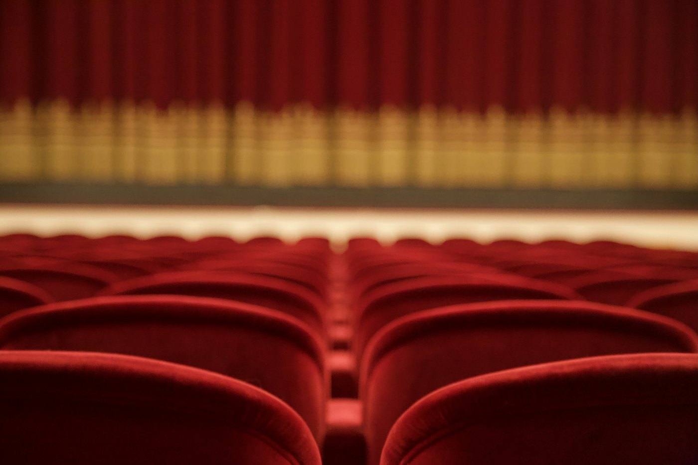 Red velvet seats in front of a stage curtain